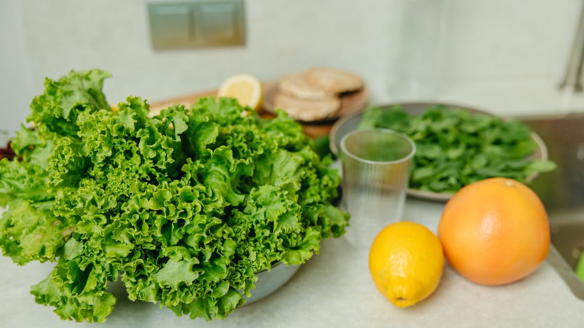 A vibrant display of fresh green lettuce and citrus fruits on a kitchen table.